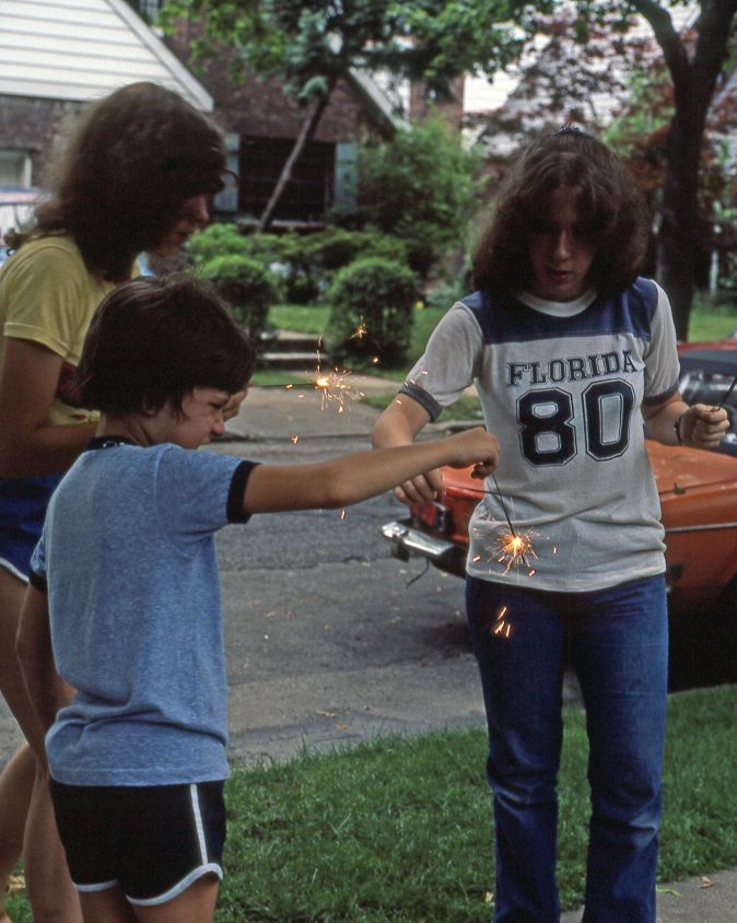 three people holding lit sparklers in their hands on fitchett street near 64th road, in the rego park neighborhood, queens, new york, new york, july 4, 1981
