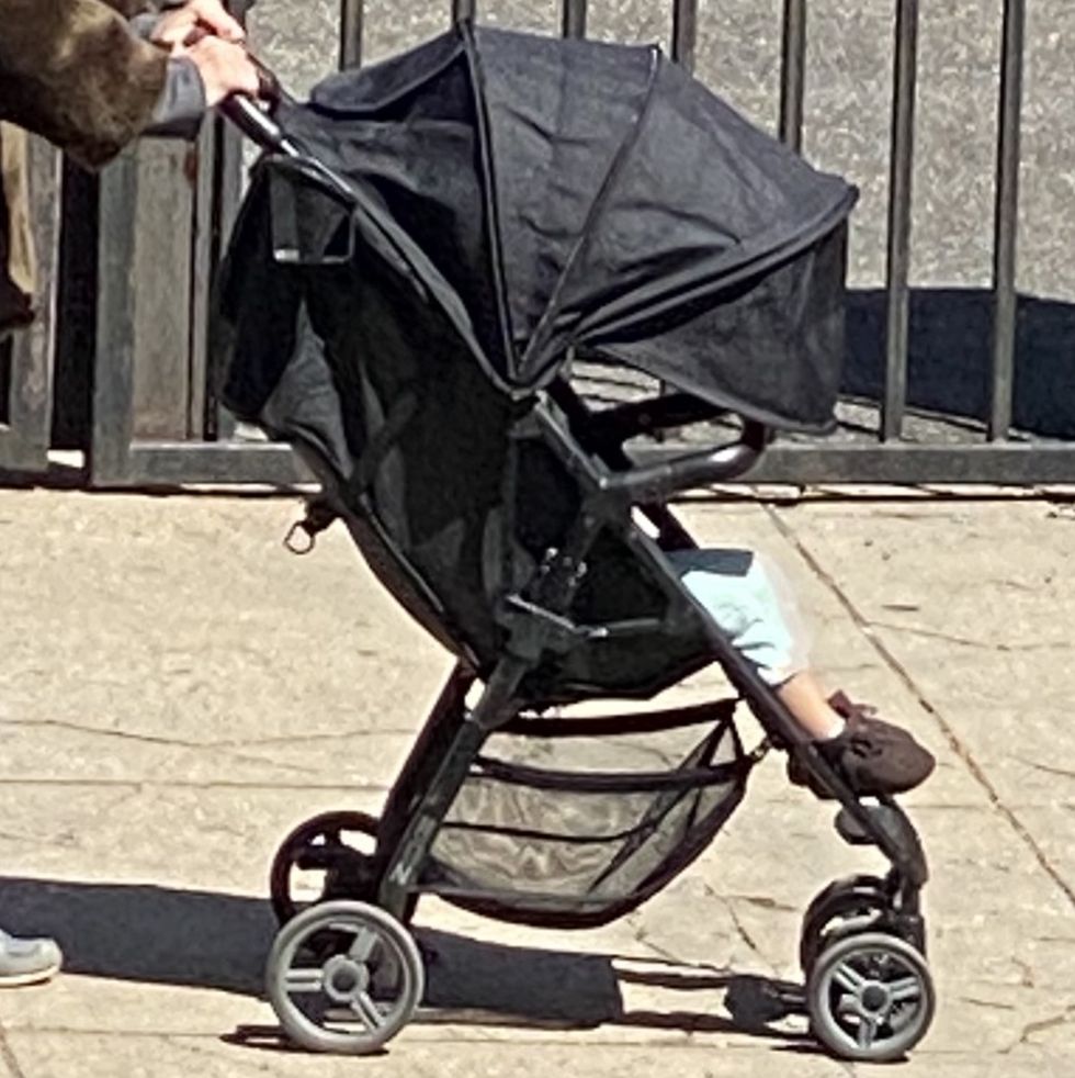 black stroller with a child inside being pushed by a parent down a street in brooklyn