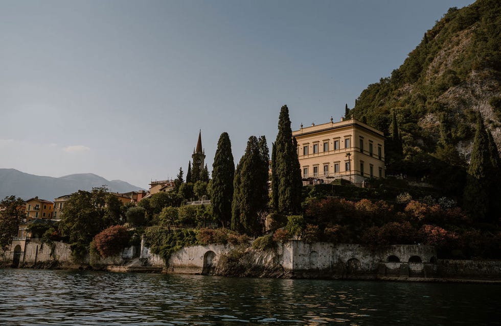 historic villa by the water surrounded by trees and mountains