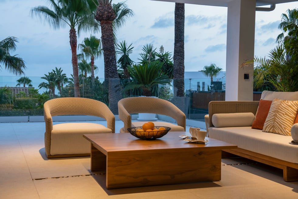 terraza con mesa de teca y sofá y sillones curvados