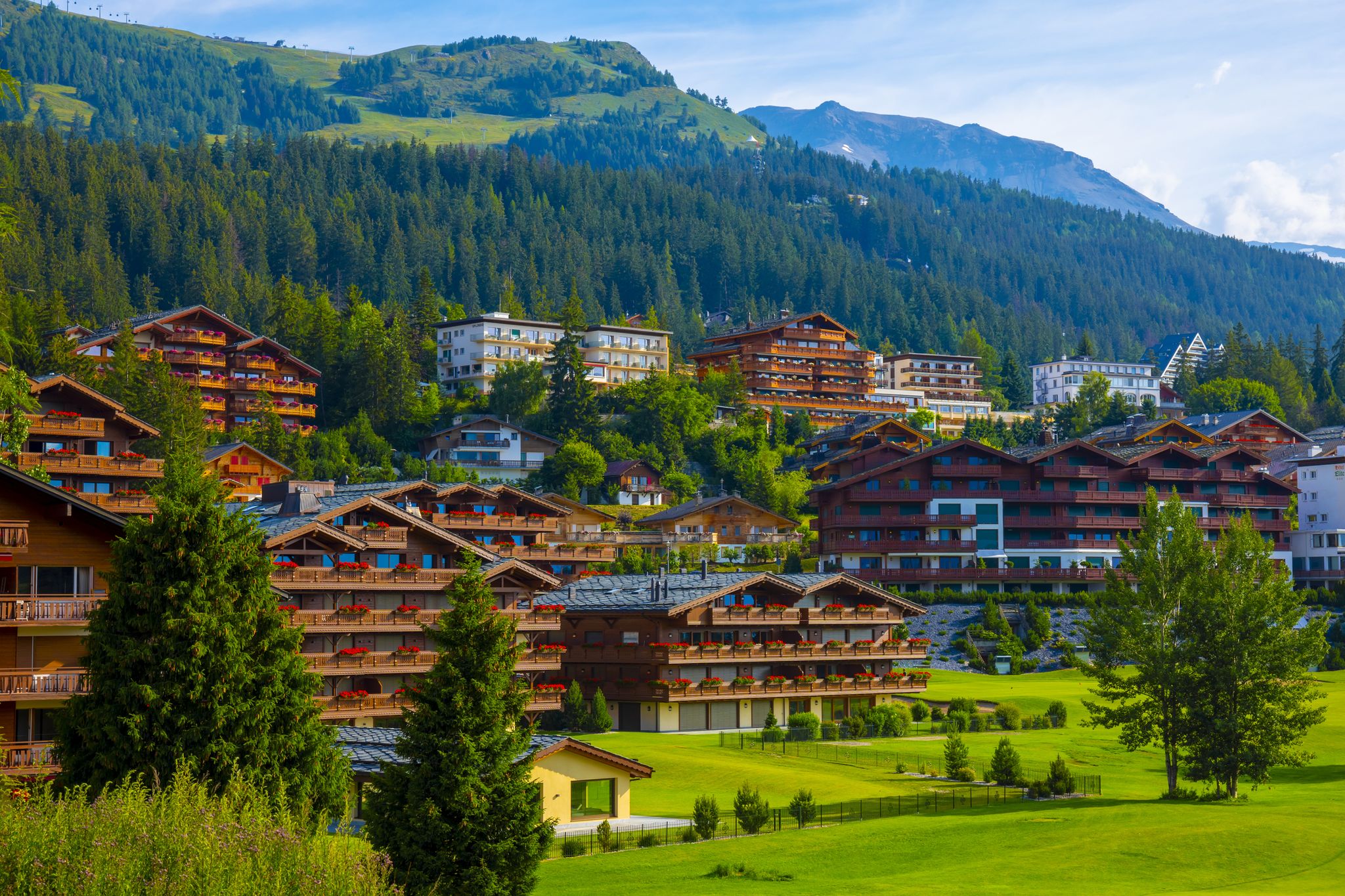 village with house and hotel with panoramic view over mountain with clouds in a sunny summer day in crans montana