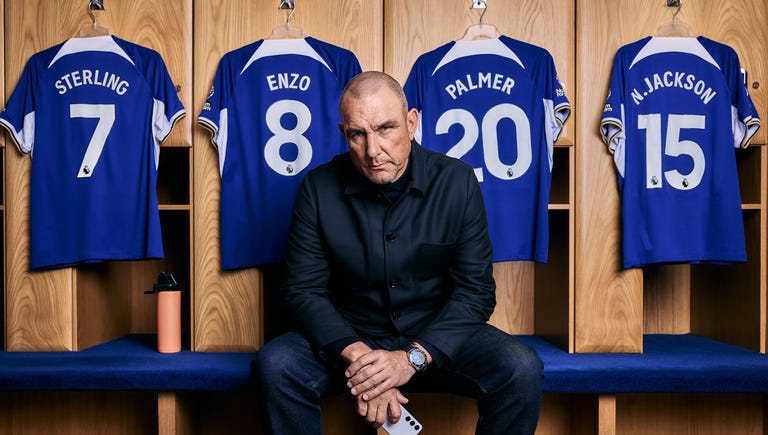 a man sitting on a bench with a group of jerseys behind him