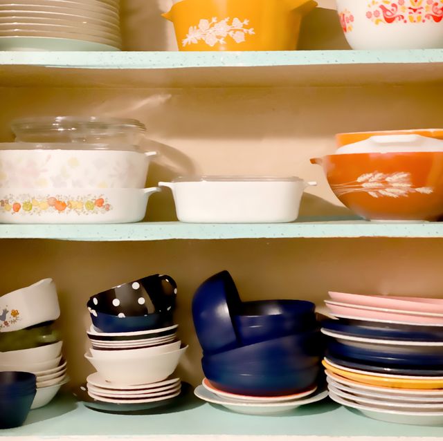 vintage 1950s white wall kitchen cabinets open revealing shelves of old fashioned kitchenware