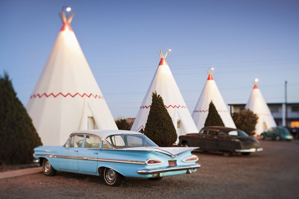 vintage cars parked by wigwam motel rooms