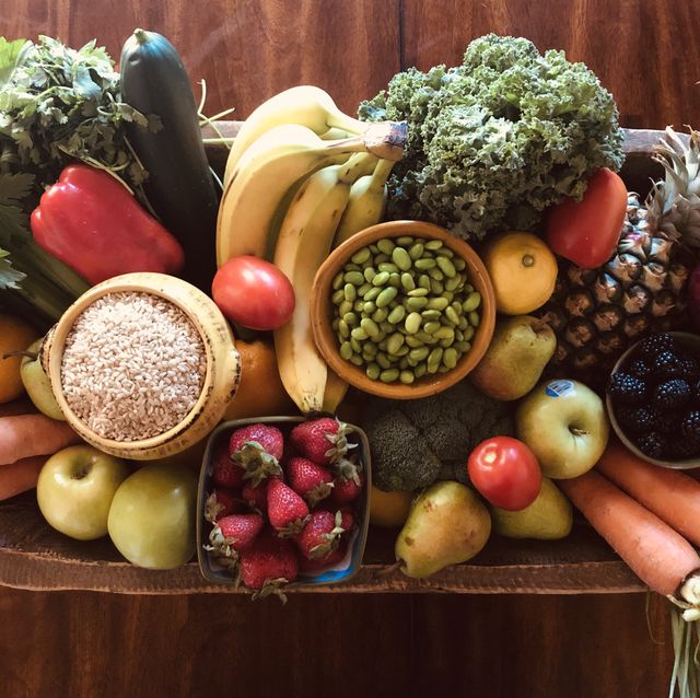 a vintage dough bowl is filled with fresh organic fruits and vegetables