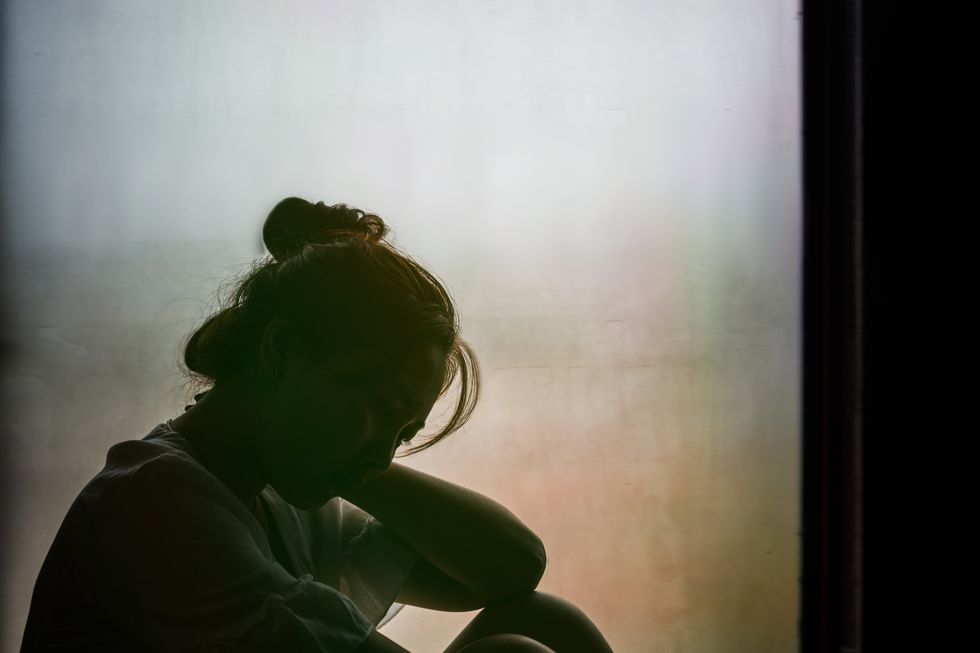 vintage filtered on silhouette of depressed girl sitting on the window