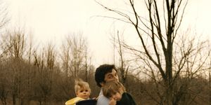 vintage late 1960s photo of young dad carrying kids on a walk in the woods