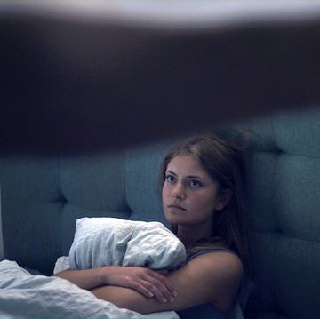 scared woman hugging a pillow in bed
