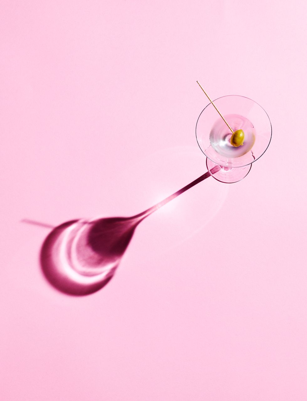 a martini cocktail in a glass against a pink background