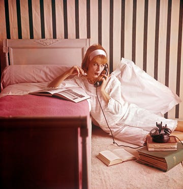 a woman in pajamas speaking over the phone in a pink bedroom 1960s photo by mondadori via getty images