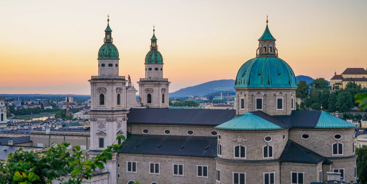 Great reasons to visit Salzberg a sunset view of the exterior of the iconic salzburg cathedral in old salzburg, austria the sunset sky is visible in the background towers of the cathedral, and some buildings of old salzburg town are visible in the foreground