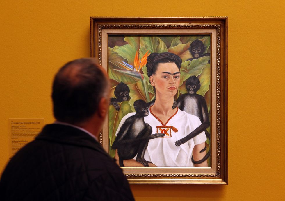 a visitor looks at a painting by mexican