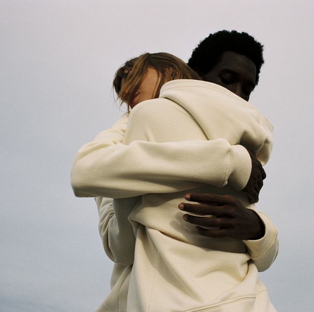 twee mensen omhelzen elkaar gekleed in hoodies in de buitenlucht