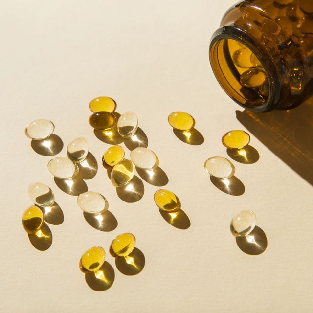 vitamin d capsules poured out of the bottle on a beige background