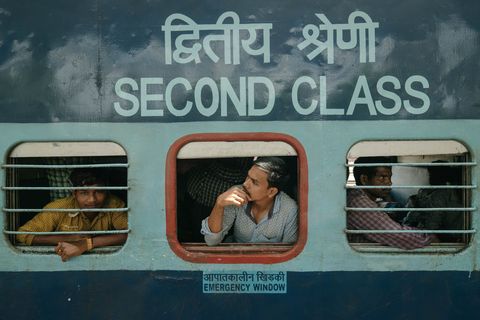 Passagiers staren uit het raampje van een tweedeklascoup Deze harde bankjes zijn de goedkoopste zitplaatsen in de trein en worden vaak ingenomen door gastarbeiders die naar hun deelstaat Assam terugkeren nadat ze in de beter betaalde bouwsector van Tamil Nadu hebben gewerkt
