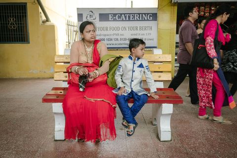Een moeder en zoon die zich voor een bruiloft hebben gekleed wachten op het perron