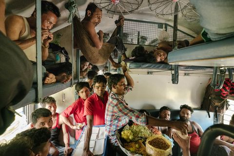 Een voedselverkoper wurmt zich door een overvolle tweedeklascoup van de Vivektrein