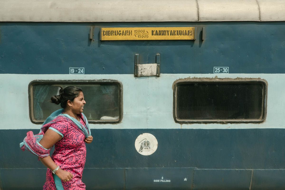 Een vrouw in een kleurige salwar kameez een broek en een lang hemd haast zich langs een tweedeklascoup
