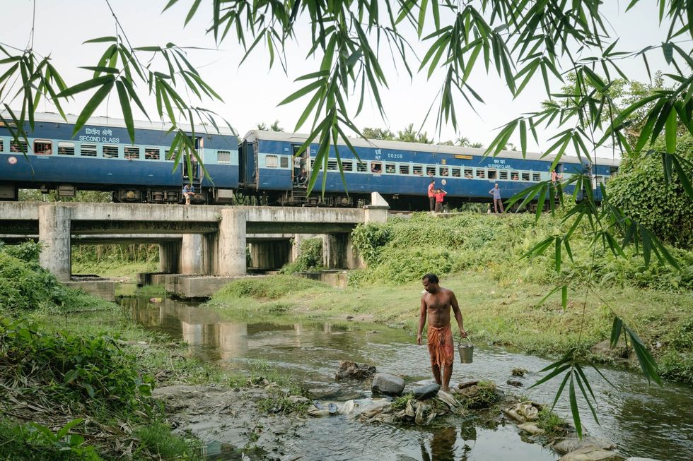 In WestBengalen neemt een man een bad in de rivier bij zijn huis Ook Paley had tijd om voor het vertrek van de trein zijn overhemd te wassen