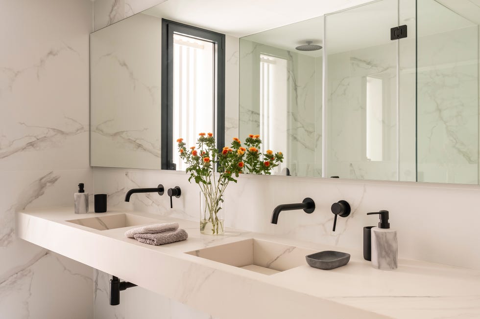 baño doble con revestimientos de mármol mate y grifería negra