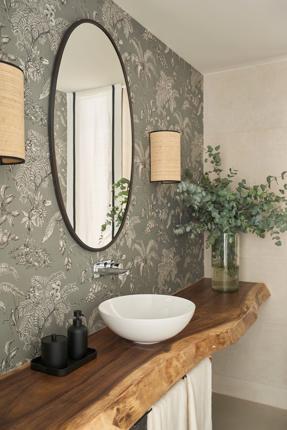 baño con papel pintado floral y encimera de madera