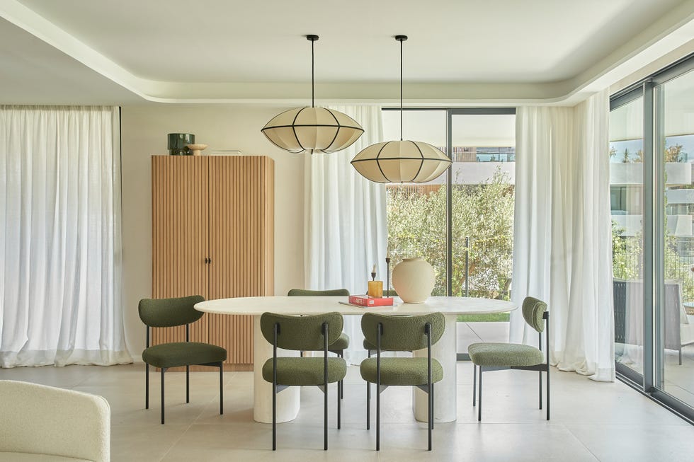 mesa de comedor blanca ovalada con sillas verdes