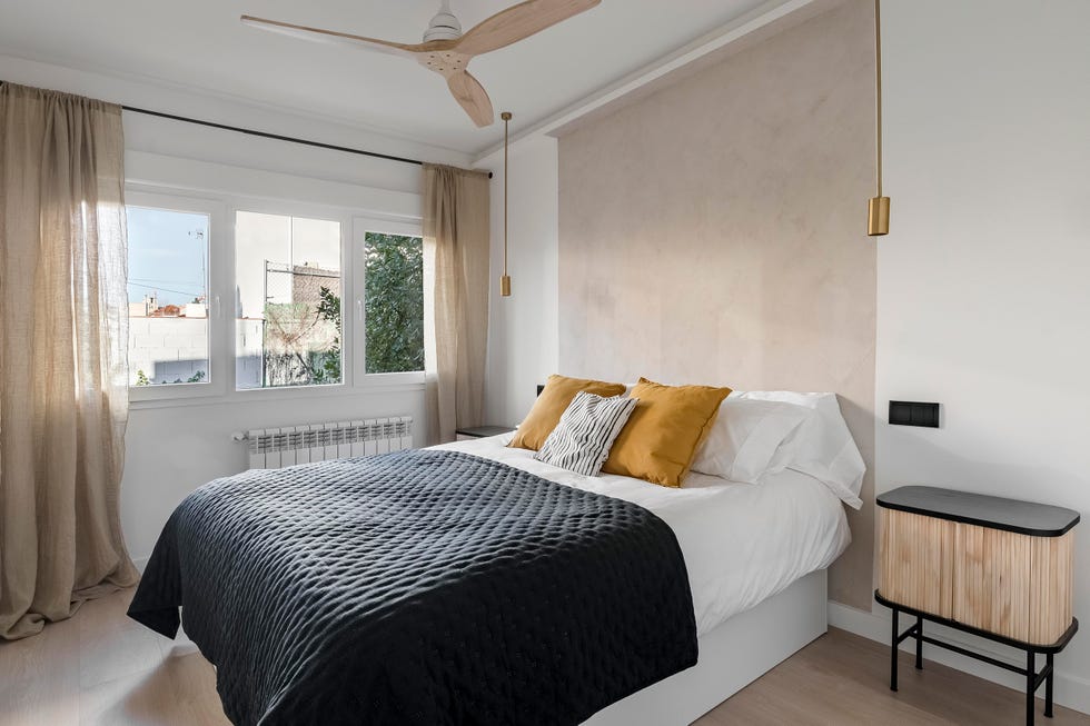 dormitorio con mesillas de madera modernas y lámparas doradas colgantes