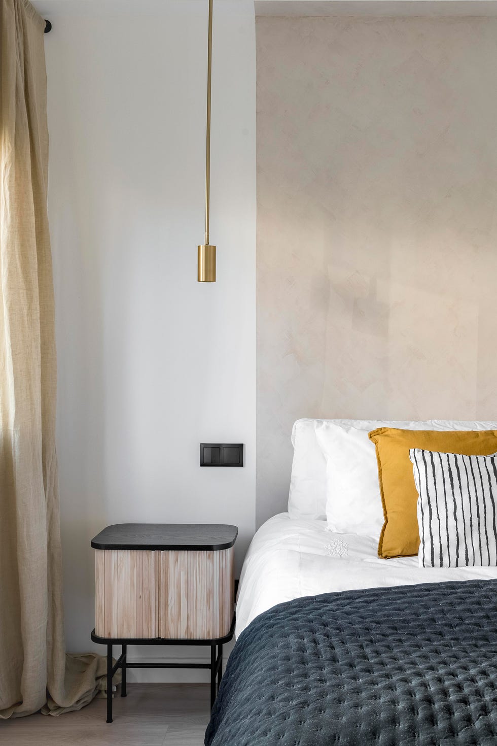 dormitorio con mesillas de madera modernas y lámparas doradas colgantes