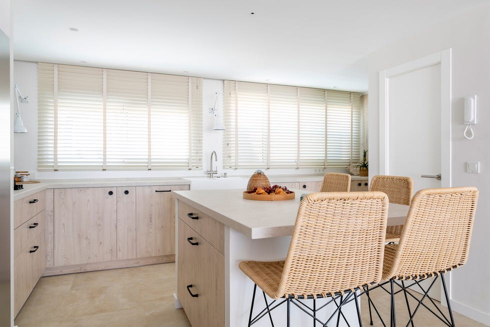 cocina con frentes de madera e isla central con taburetes