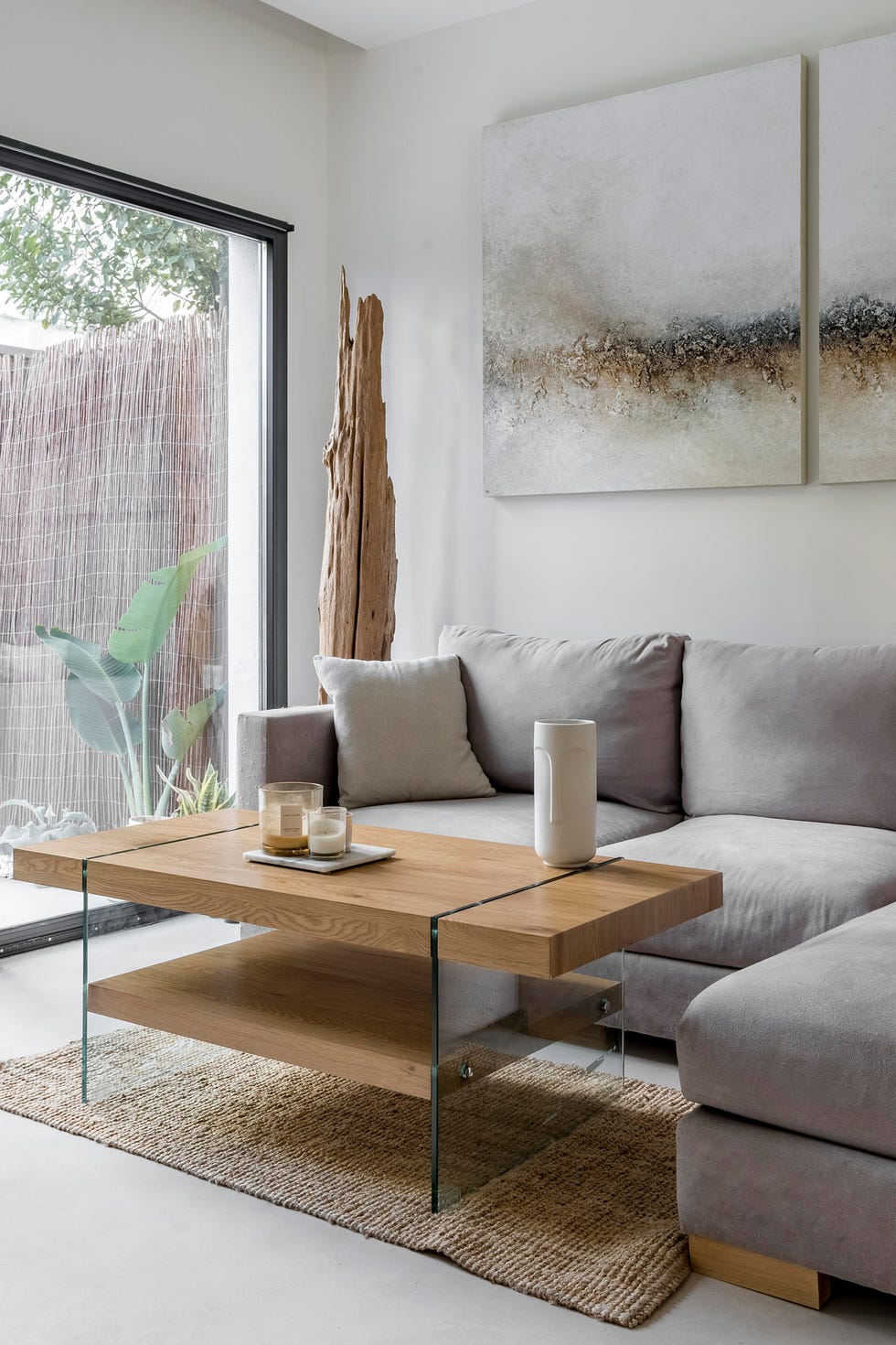 sofá con chaiselongue gris y mesa de centro de madera sobre alfombra de yute