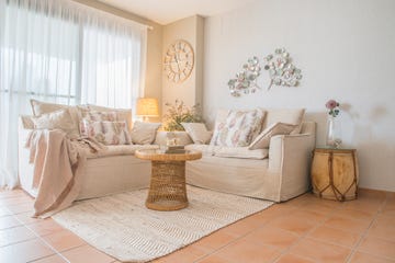 salón rústico mediterráneo con sofá en l de lino natural y mesa de centro de fibras redonda