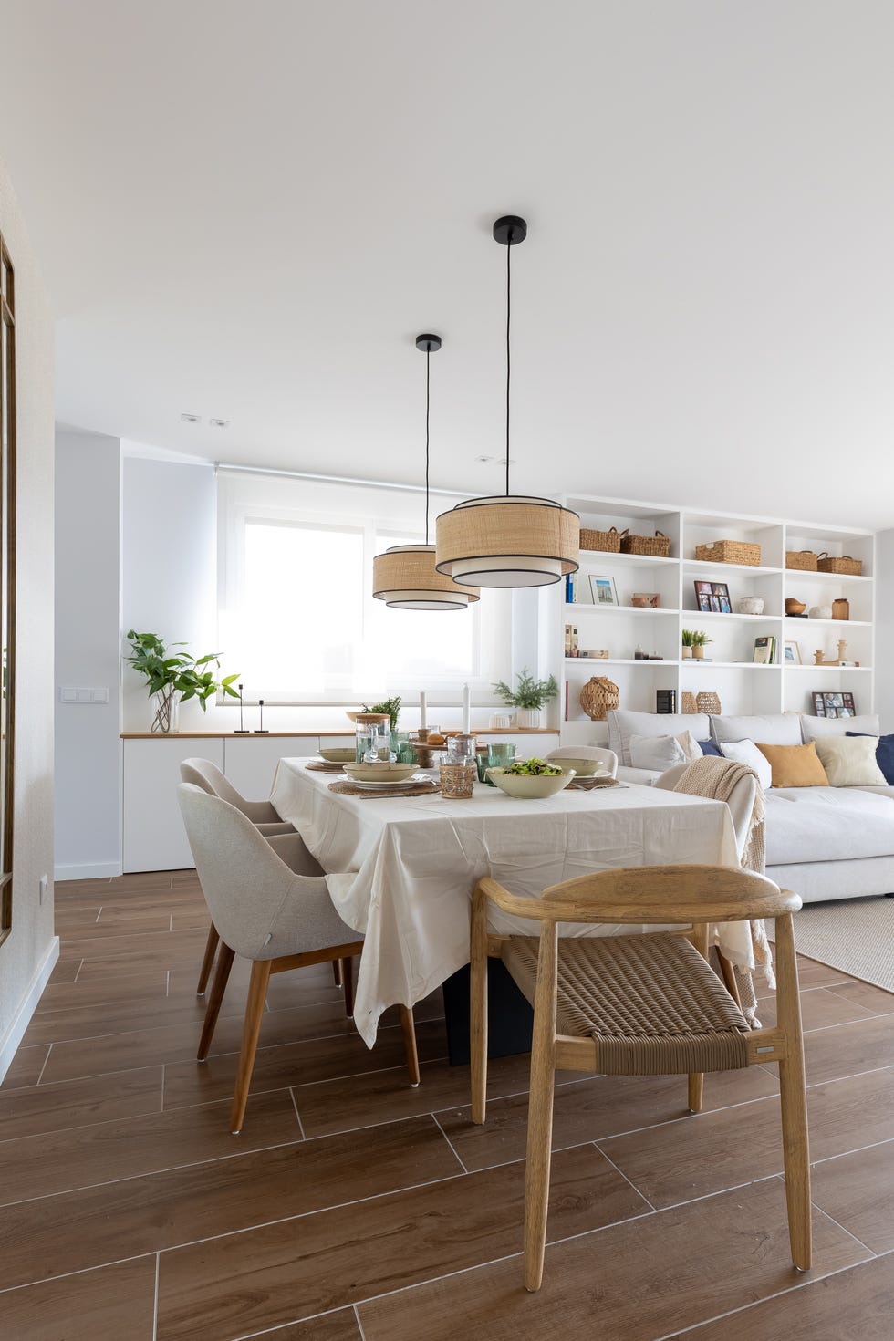comedor con sillas tapizadas en beige, sillas de madera y lámparas suspendidas con pantallas redondas