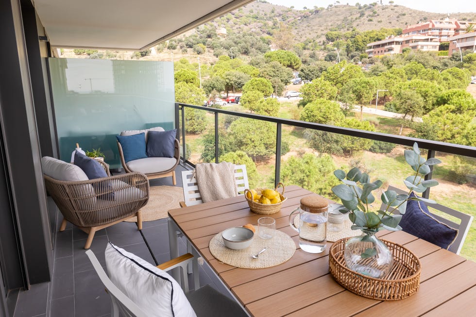 terraza con mesa de comedor, dos butacas y alfombra de yute redonda