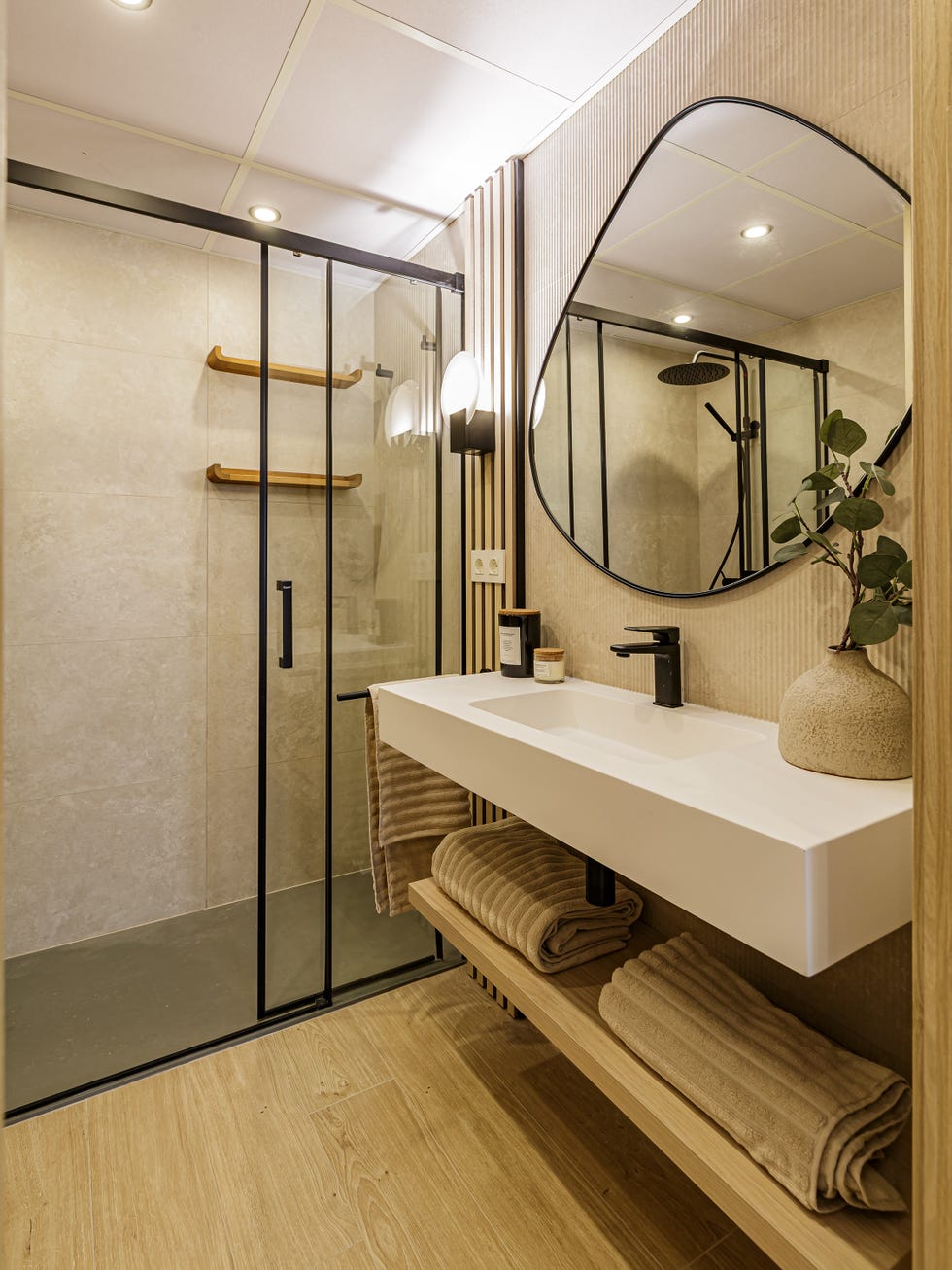 baño con lavabo volado y espejo con forma orgánica