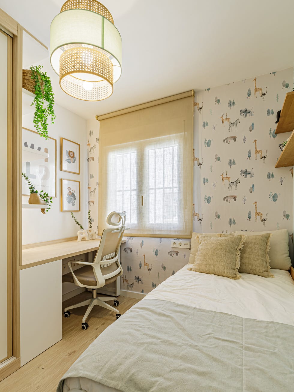 habitación infantil con cama individual, escritorio y papel pintado con motivos de fauna y flora