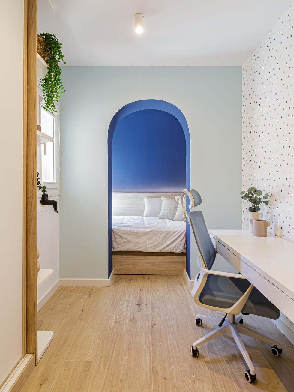 habitación infantil con escritorio y cama detrás de un arco