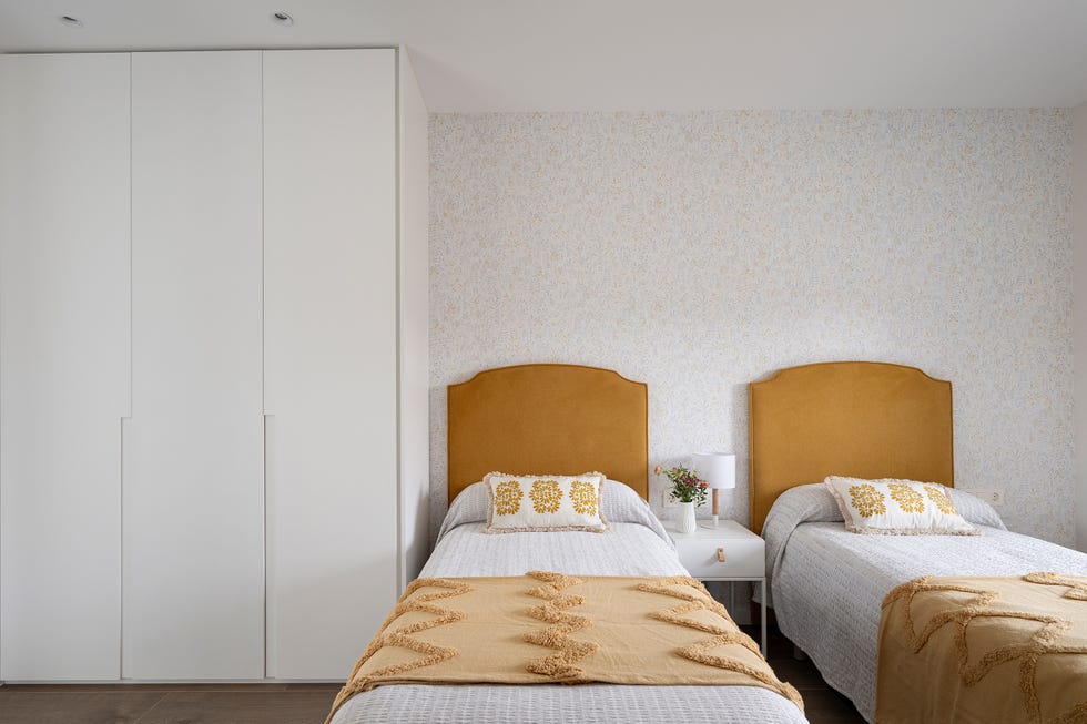 habitación con dos camas individuales con cabeceros tapizado en color mostaza