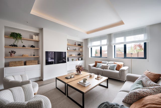 salón con sofás, butacas, dos mesas de centro de madera y dos estanterías de obra con baldas de madera