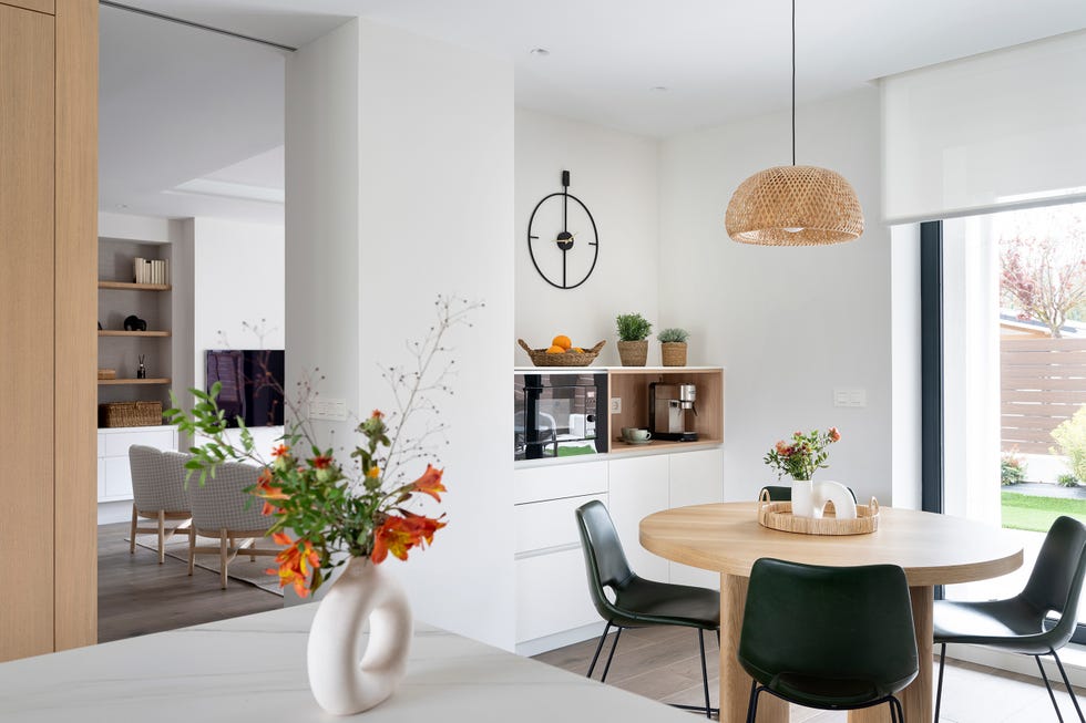 cocina abierta con mesa de comedor de madera redonda con sillas de piel y lámpara de fibras