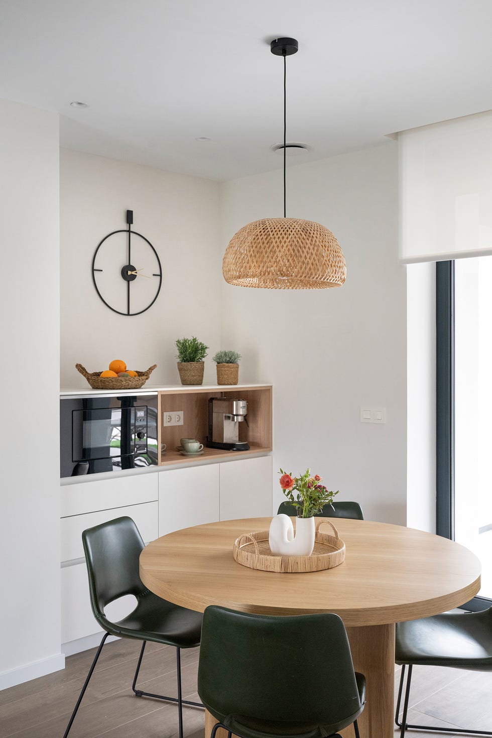 cocina con mesa de comedor de madera redonda con sillas de piel y lámpara de fibras