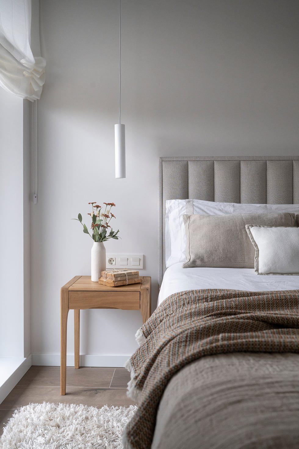 habitación con cabecero tapizado en gris y mesita de madera