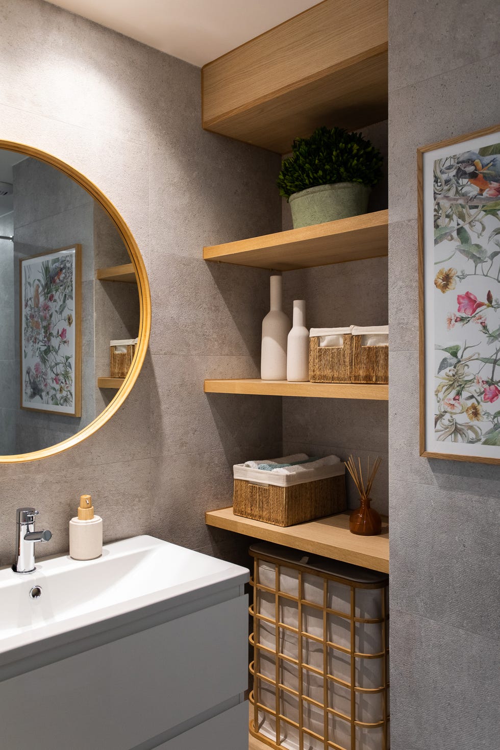 baño con mueble gris, espejo redondo y baldas de madera