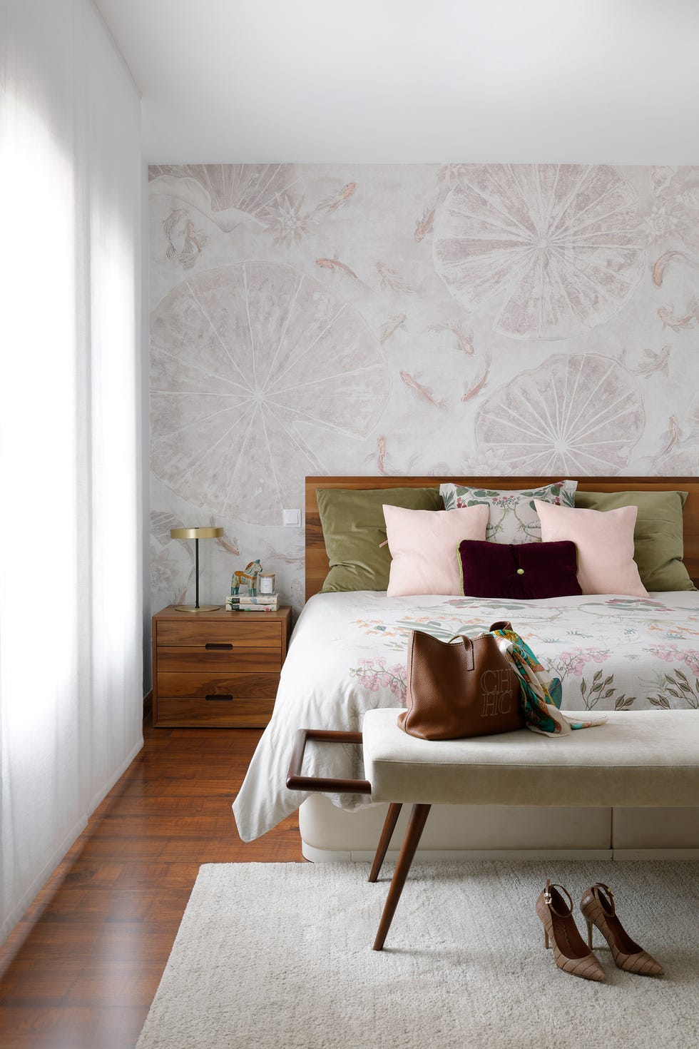 dormitorio con cabecero y mesita de madera, papel pintado y banco tapizado en beige