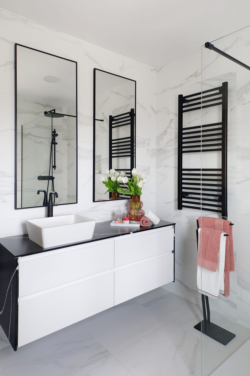 baño con revestimientos de mármol y mueble volado en blanco y mármol negro