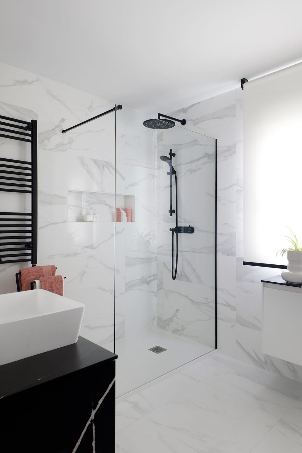 baño con ducha, revestimientos de mármol y accesorios negros