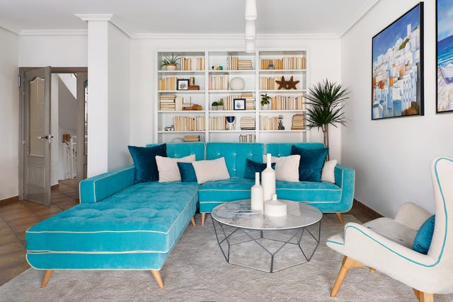 salón con sofá con chaise longue de terciopelo azul y mesa de centro redonda
