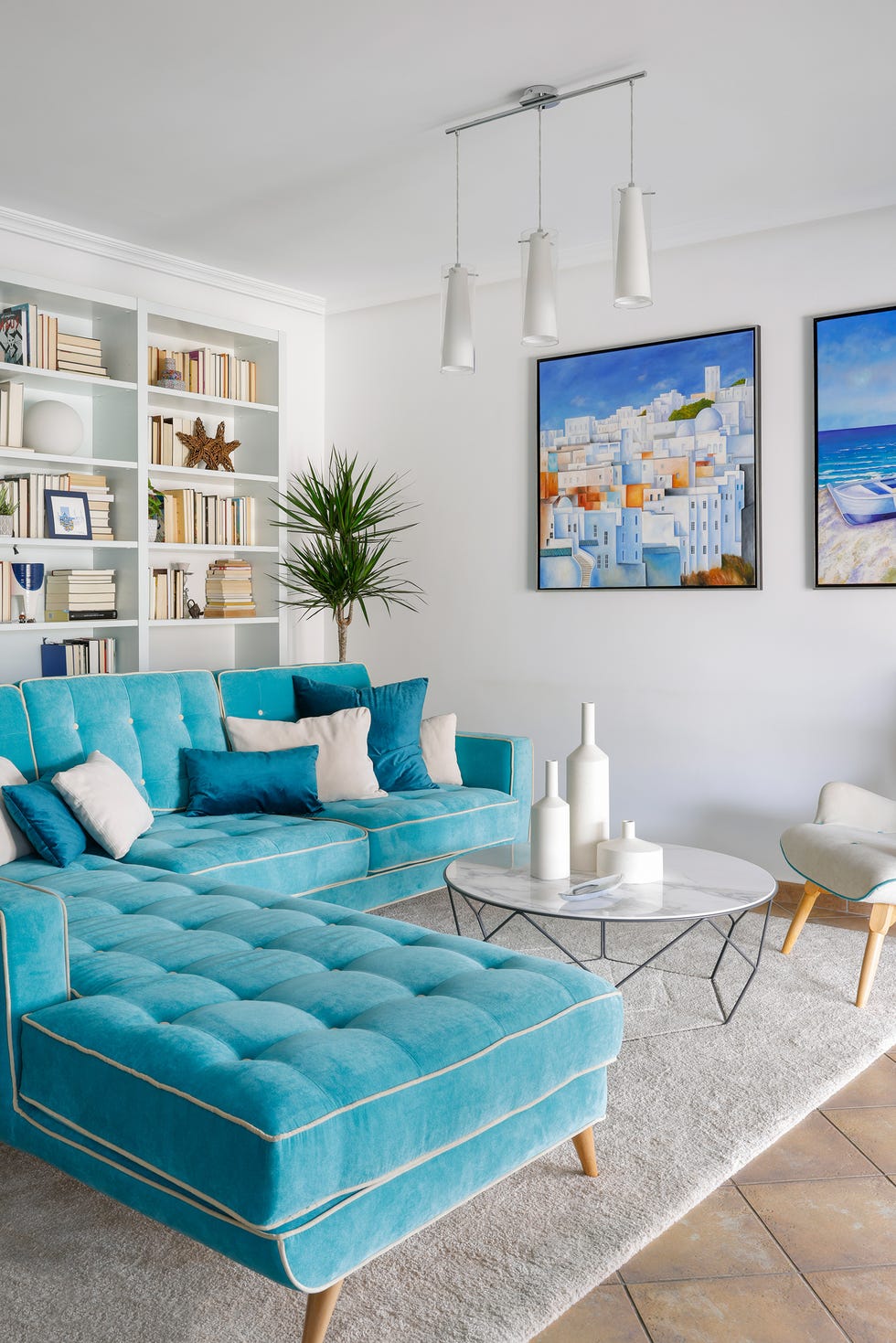 salón con sofá con chaise longue de terciopelo azul y mesa de centro redonda