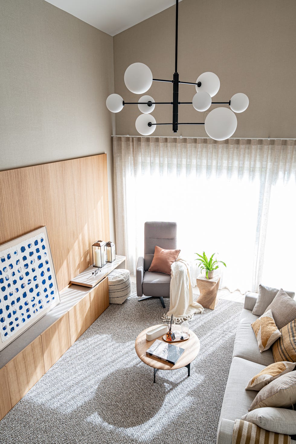 salón con mueble de tv de madera, sofá y butaca giratoria frente a mesa de centro redonda