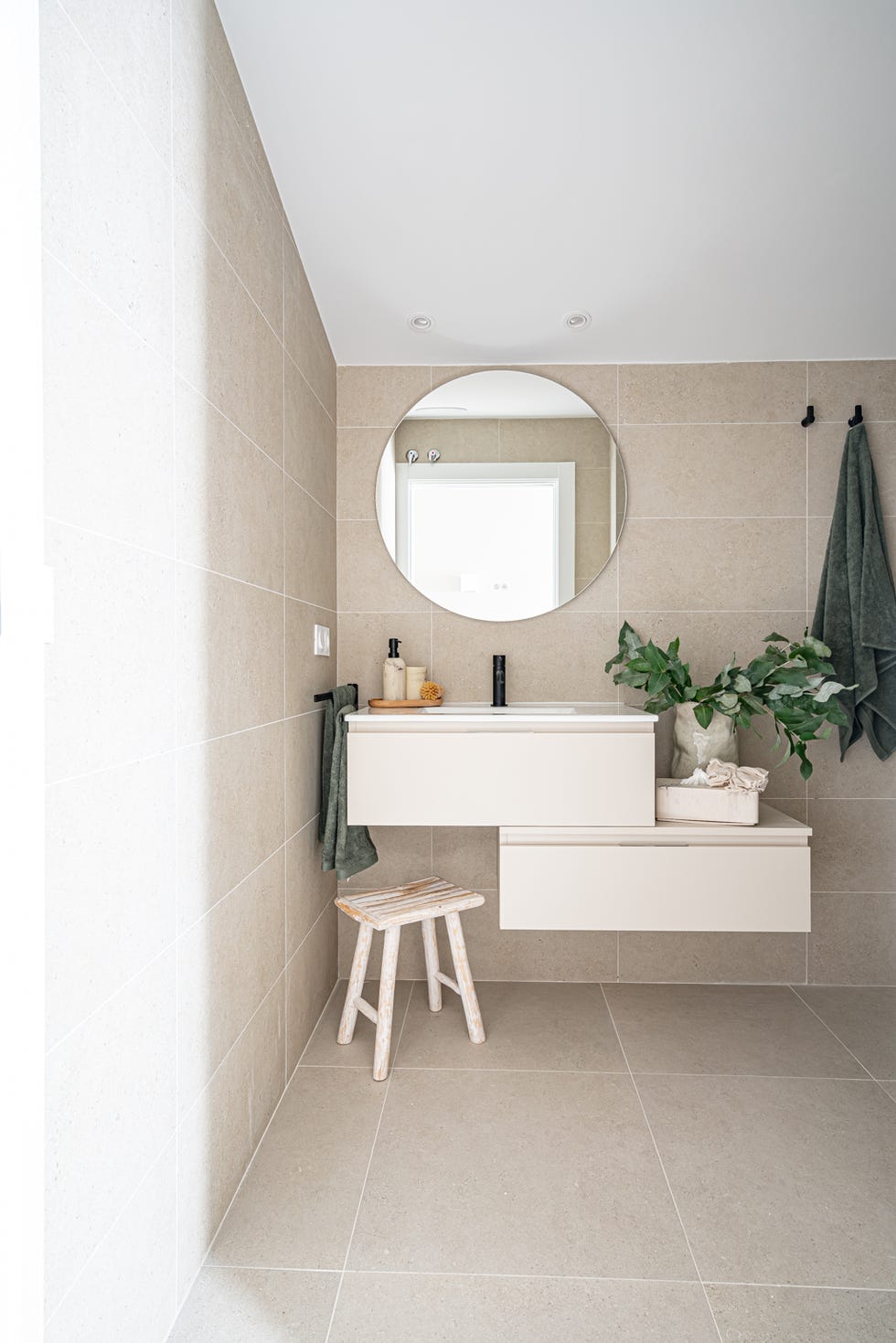 baño con mueble volado irregular y espejo redondo