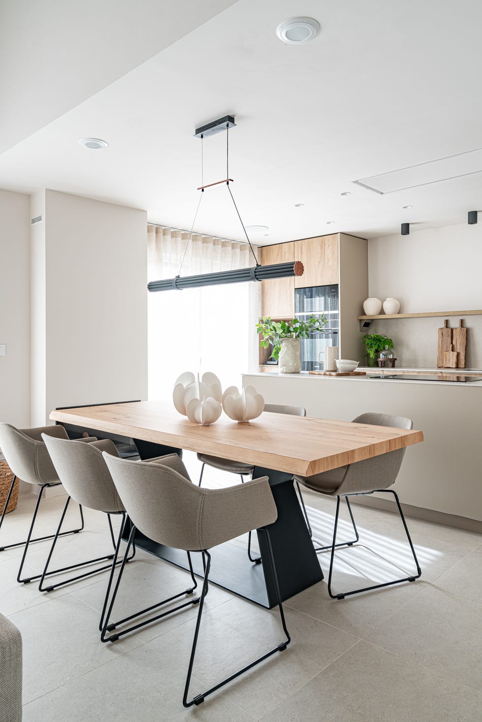 mesa de comedor con soporte de acero y sobre de madera, sillas y lámpara suspendida